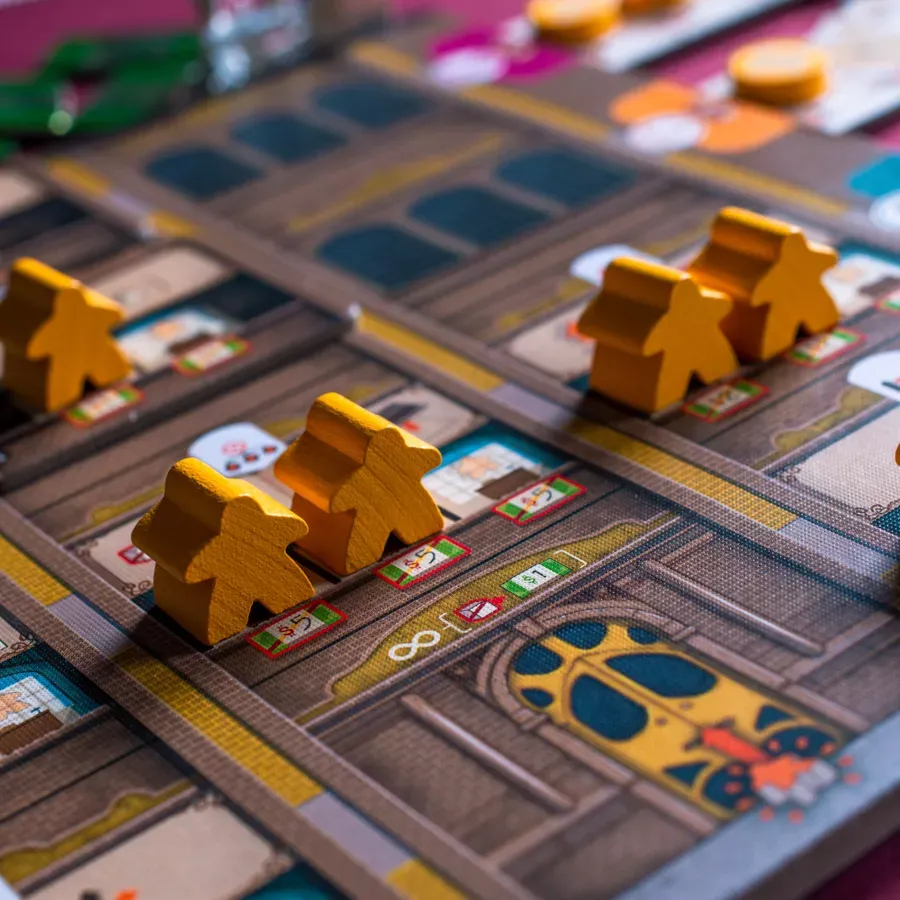 Yellow wooden worker pieces standing on the department board of the board game Carnegie